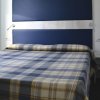 Letto matrimoniale con copriletto a quadri e testiera blu.