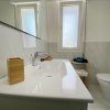 Bagno moderno bianco con lavabo, specchio e finestra.