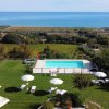 Panoramica di piscina, prato e mare sullo sfondo.