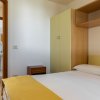 Letto matrimoniale con copriletto giallo, armadio e comodino.