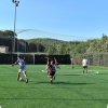 Calciatori in campo sintetico recintato, cielo sereno.