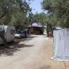 Area campeggio con roulotte, auto e alberi.