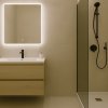 Bagno moderno con doccia nera e specchio illuminato.