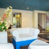 Sala d'attesa moderna con divani bianchi e grandi fiori decorativi.