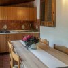 Cucina esterna con tavolo, fiori e armadietti in legno.