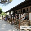 Una fila di villette a schiera con scale esterne in legno e pietra, circondate da alberi.