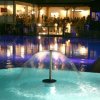 Piscina notturna illuminata con fontana al centro.