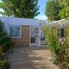 Un bungalow moderno circondato da alberi e piante con una veranda in legno.