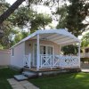 Bungalow con veranda bianca, circondato da alberi.