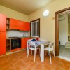 Cucina moderna con mobili arancioni e tavolo bianco.
