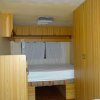 Interno di una roulotte con letto matrimoniale e armadi in legno chiaro.