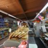 Interno di negozio alimentari con scaffali pieni e pane su bancone.
