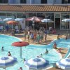 Dettaglio della piscina con persone che nuotano e intrattenimento sul bordo.