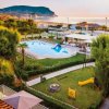 Vista su piscina e parco giochi, con mare e colline sullo sfondo.