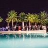 Festa notturna all'aperto vicino a una piscina, circondata da palme.