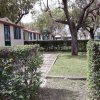 Un vialetto di mattoni tra prati e cespugli, con case e alberi sullo sfondo.