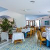 Ristorante luminoso con tavoli apparecchiati e sedie, pavimento decorato a motivi geometrici.