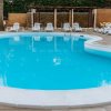 Piscina tonda, circondata da lettini bianchi.