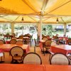 Sala da pranzo con tavoli coperti da un tendone giallo.