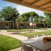 Patio coperto con tavolo e sedie, giardino e vialetti curati.