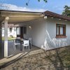 Casa con patio coperto, tavolo e sedie da esterno. Alberi e cielo azzurro sullo sfondo.
